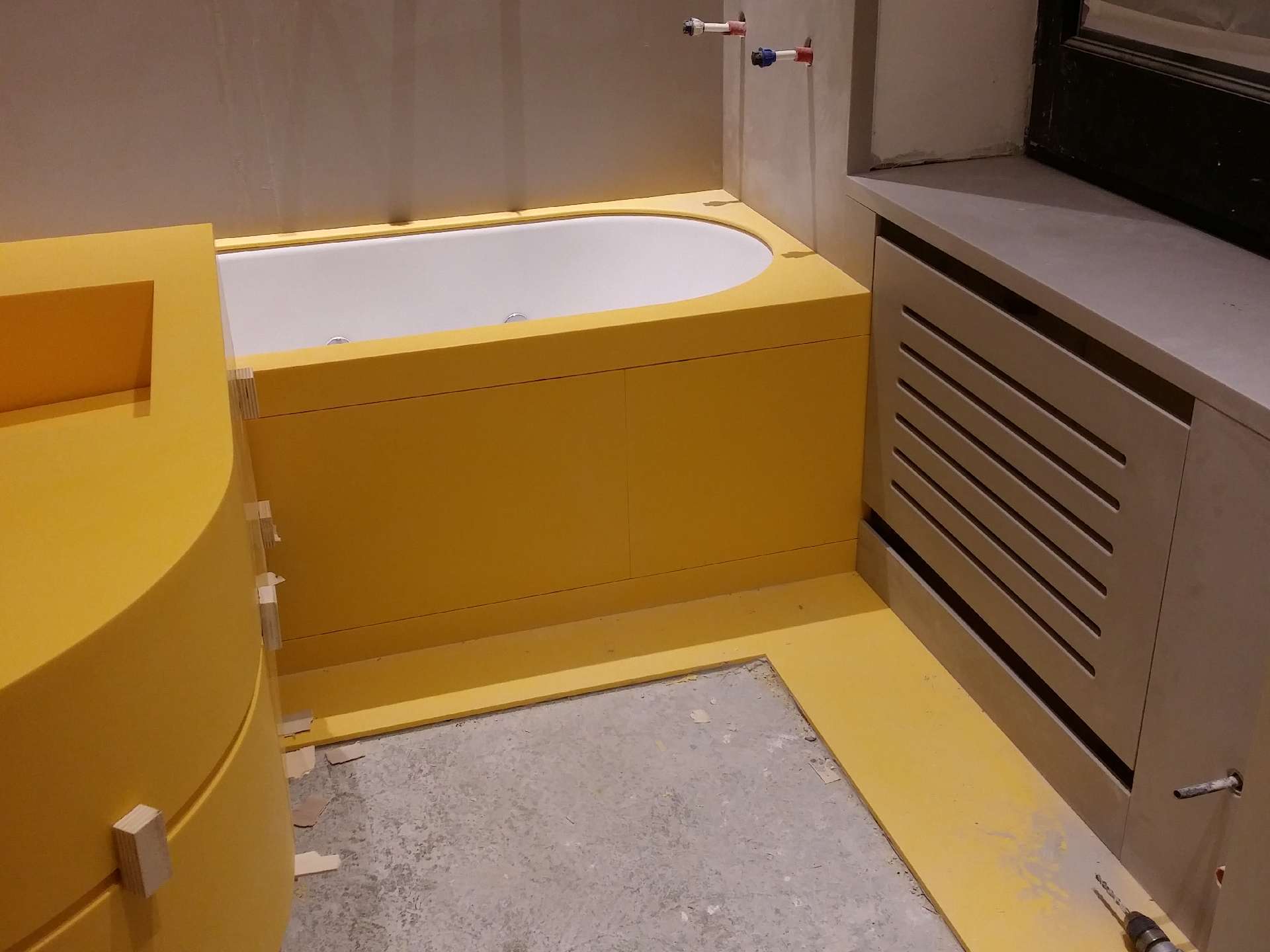 Basin cut into the yellow Corian top, with a grey Corian radiator cover