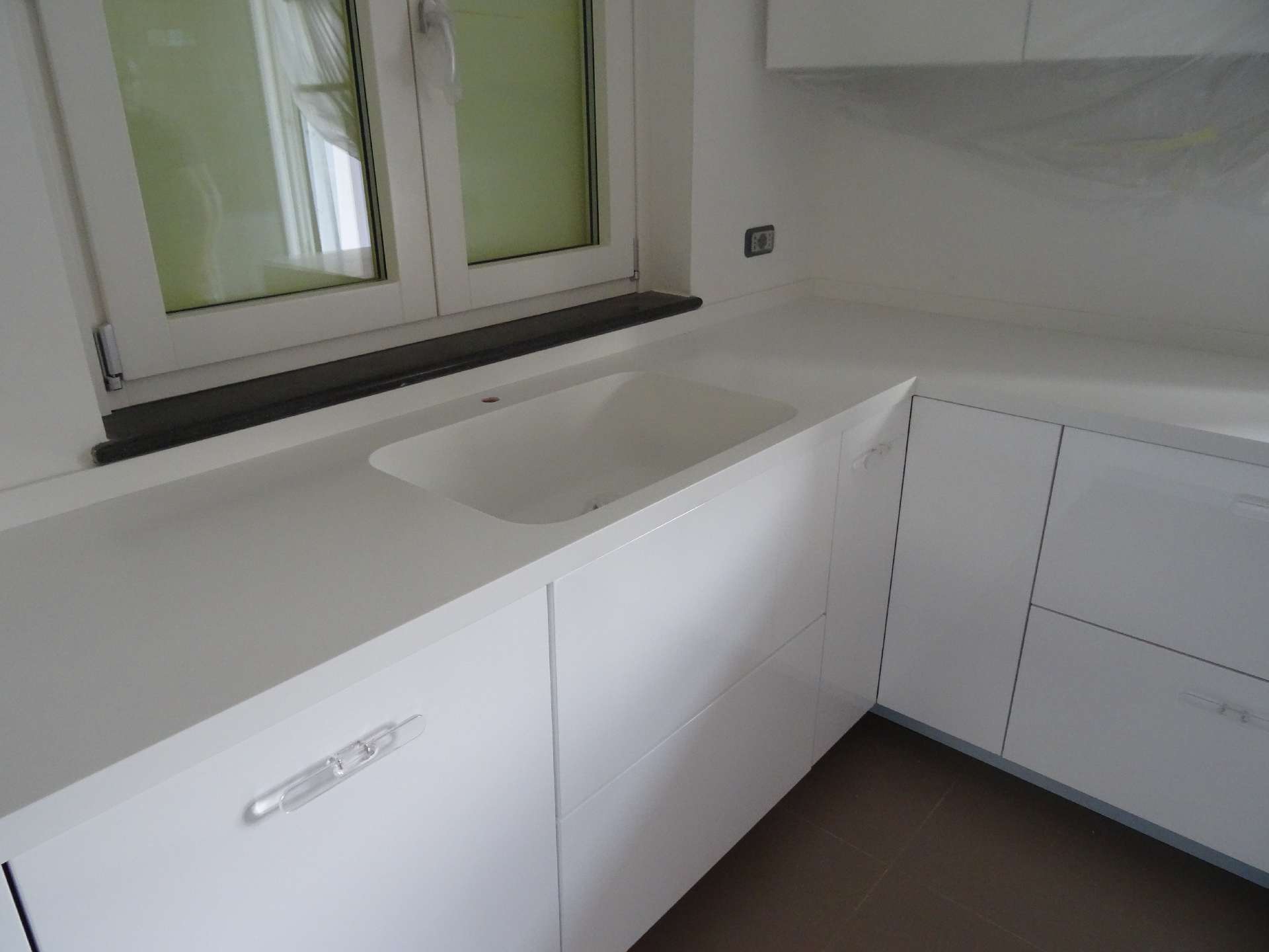 White Corian kitchen with a green splashback